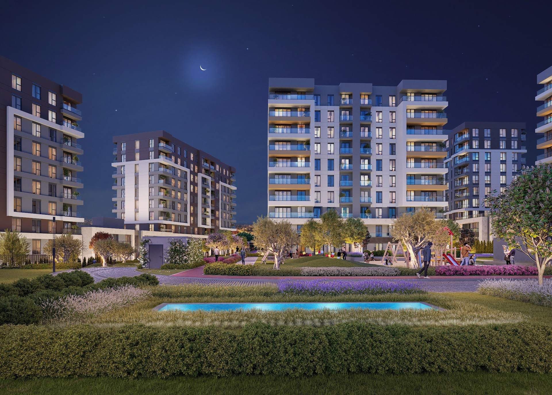 Night rendering of the residential blocks seen across a garden with a lit rectangular pool and olive trees