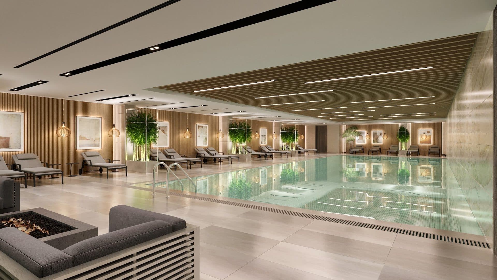 Rendering of the indoor swimming pool with loungers, planters and a seating area by a fire pit