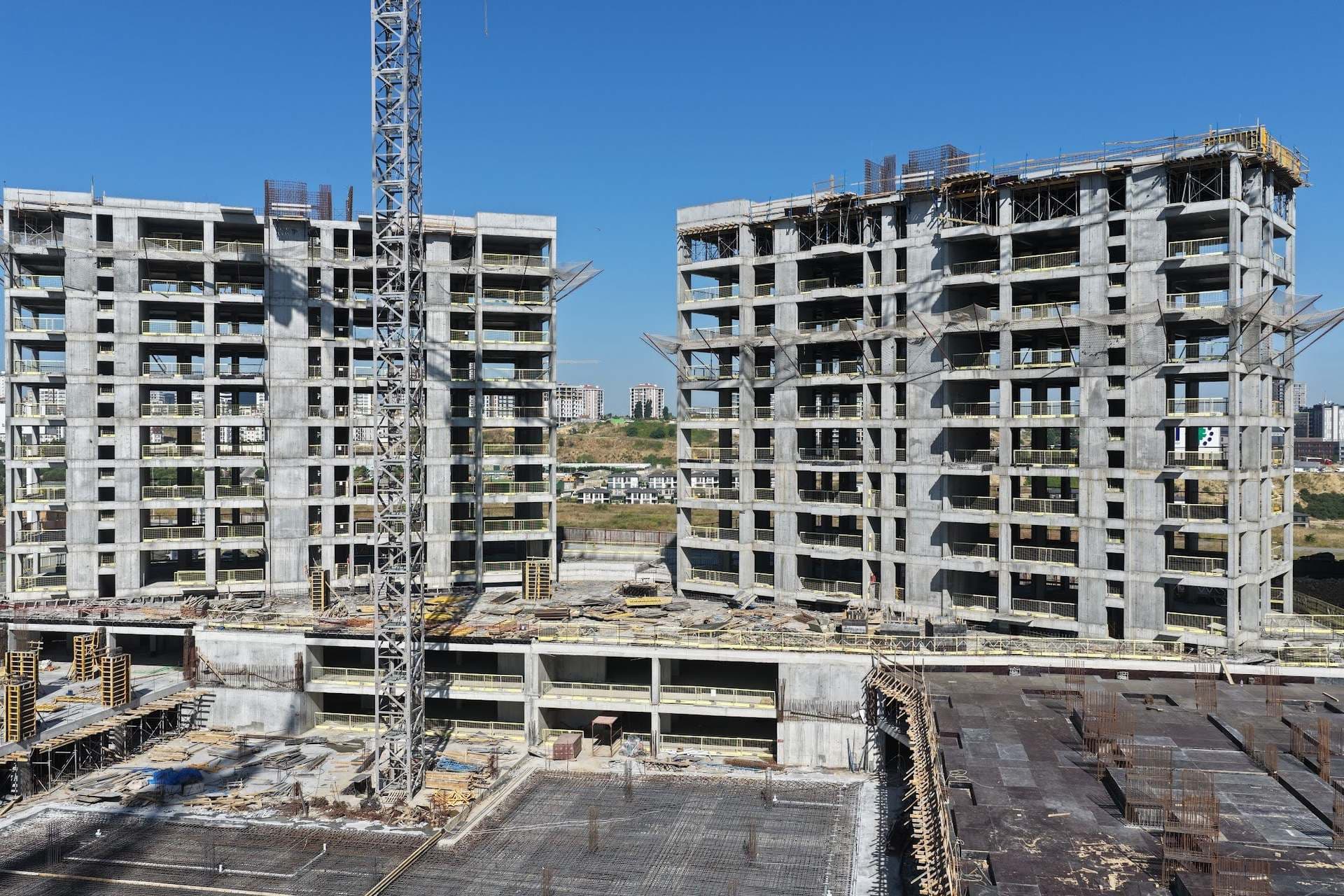 Drone photo of the two concrete frames with a tower crane, seen across the podium slab of the site
