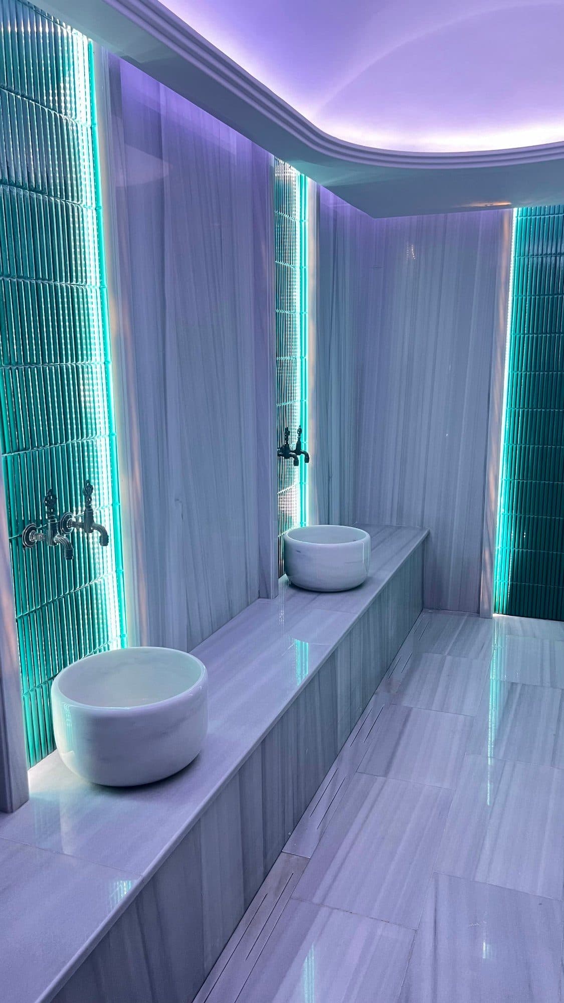 Marble Turkish bath (hamam) with stone basins, taps and colored lighting