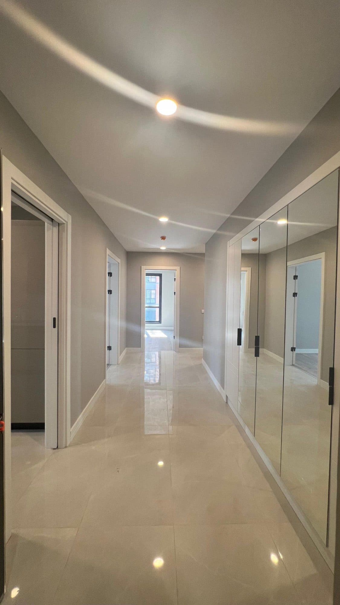Entrance hall with polished tile flooring and a wall of mirrored wardrobes