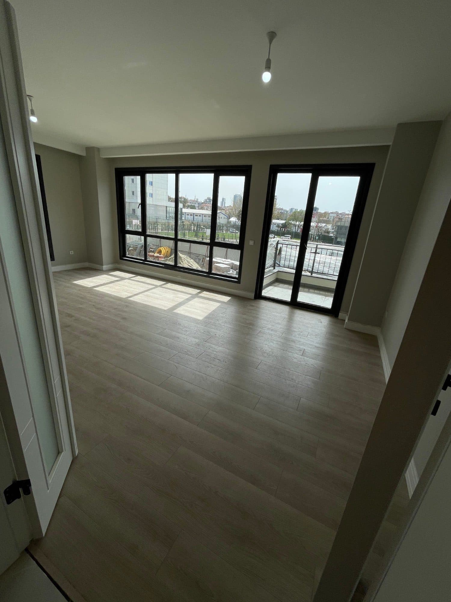 Bright room with wood-look flooring, large windows and a glazed door to the balcony