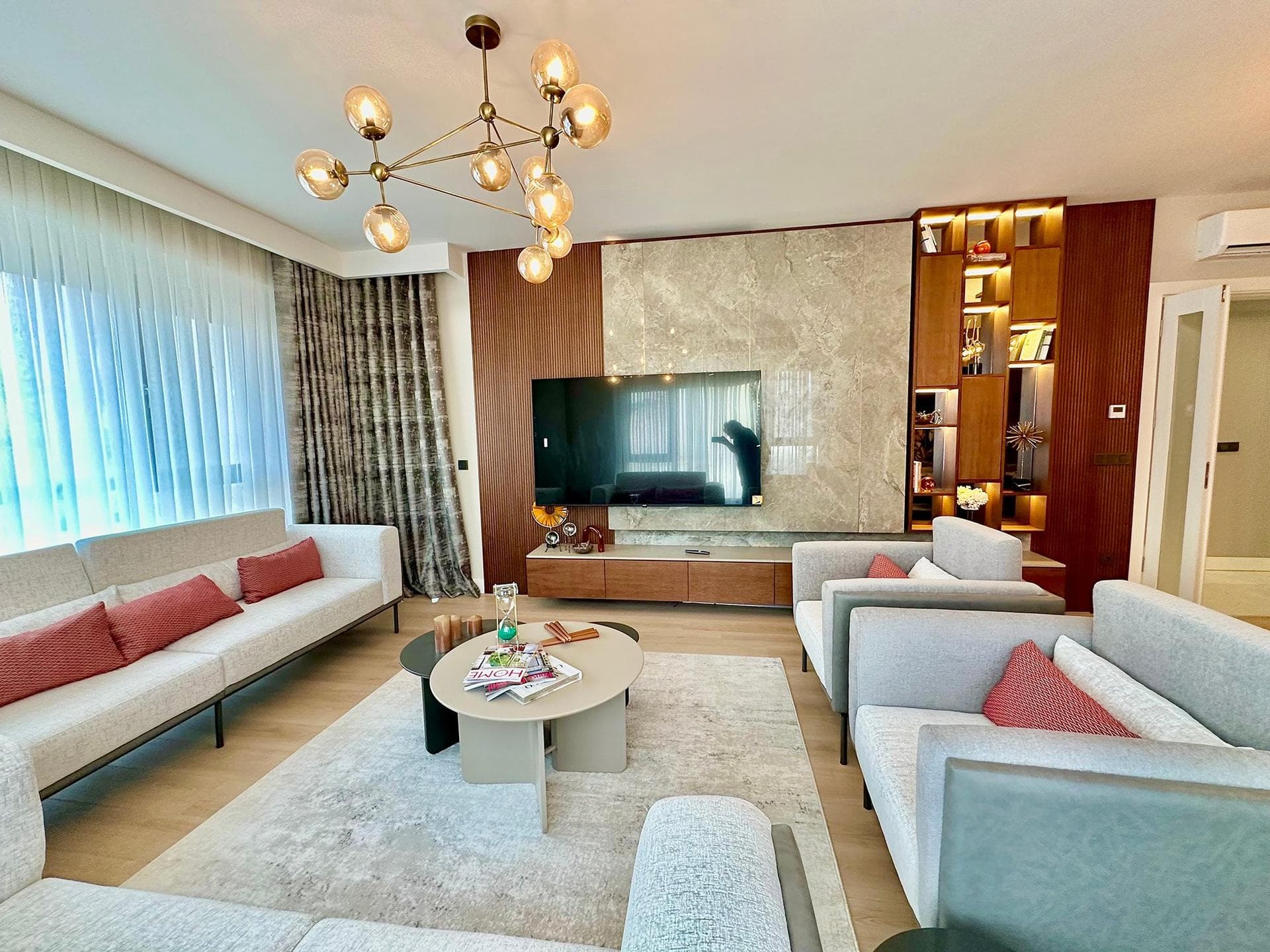 Living room of the furnished 3+1 sample apartment, with sofas and a marble-clad TV wall