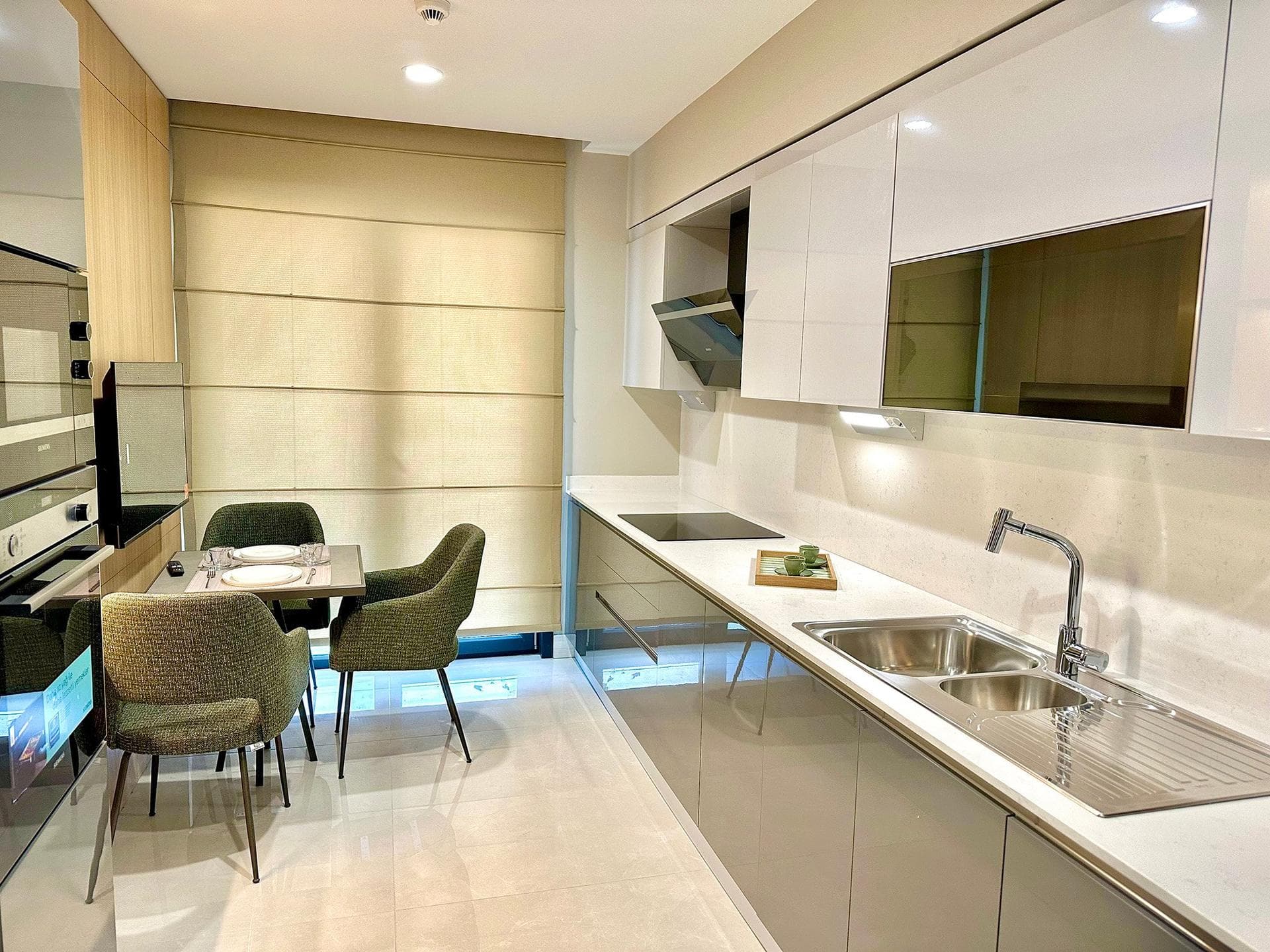 Kitchen of the 3+1 sample apartment with built-in oven, hob, double sink and a dining corner by the window