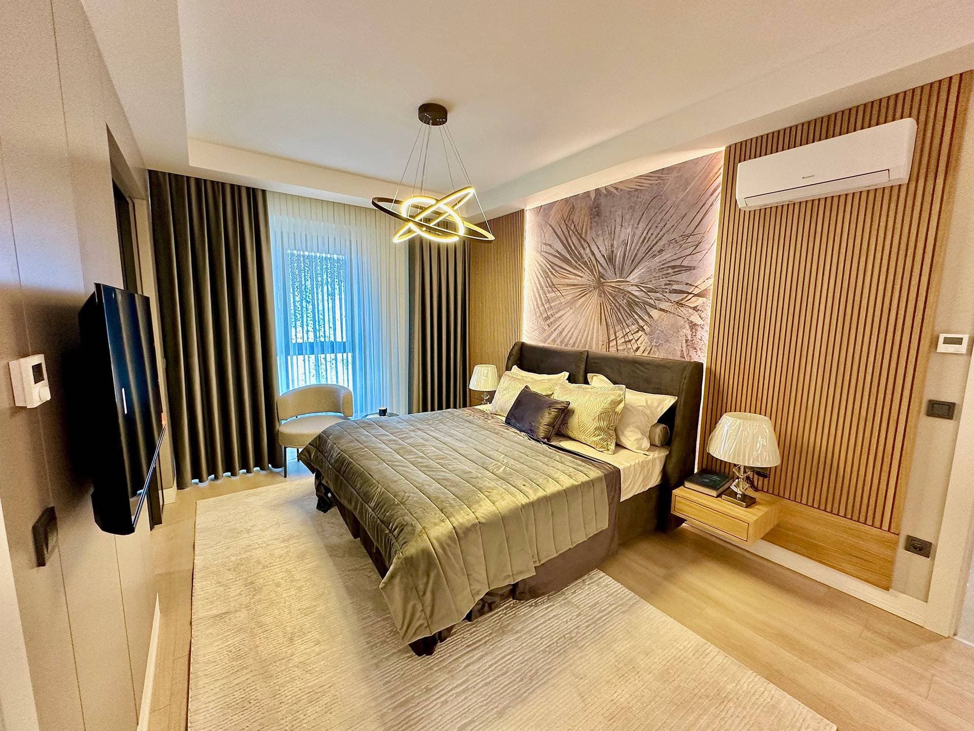 Main bedroom of the 3+1 sample apartment, with a slatted wood wall and wall-mounted air conditioner