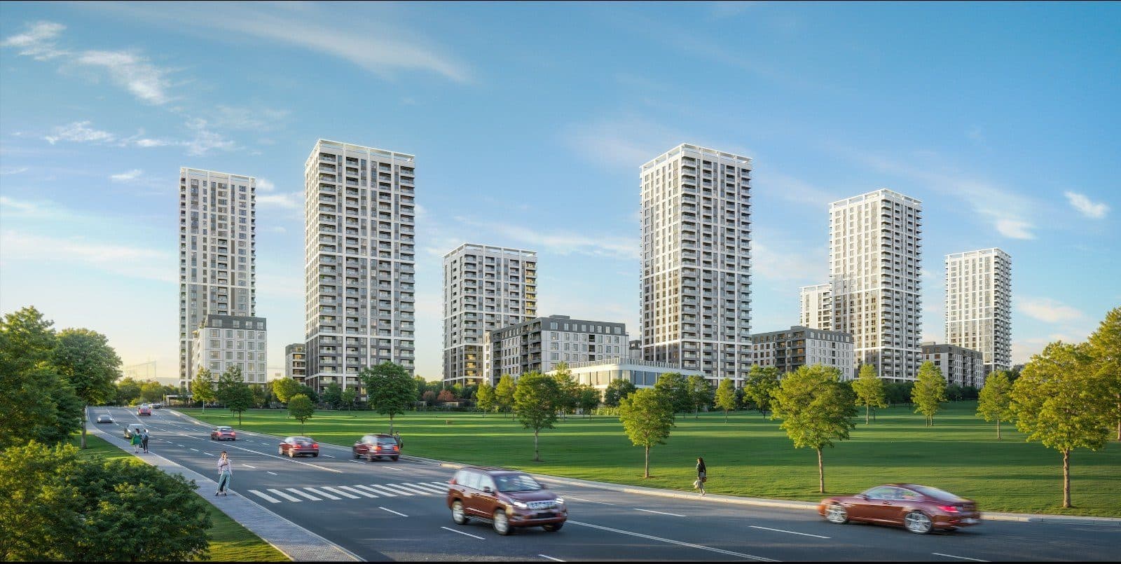 Residential towers seen across a park and a road on a sunny day