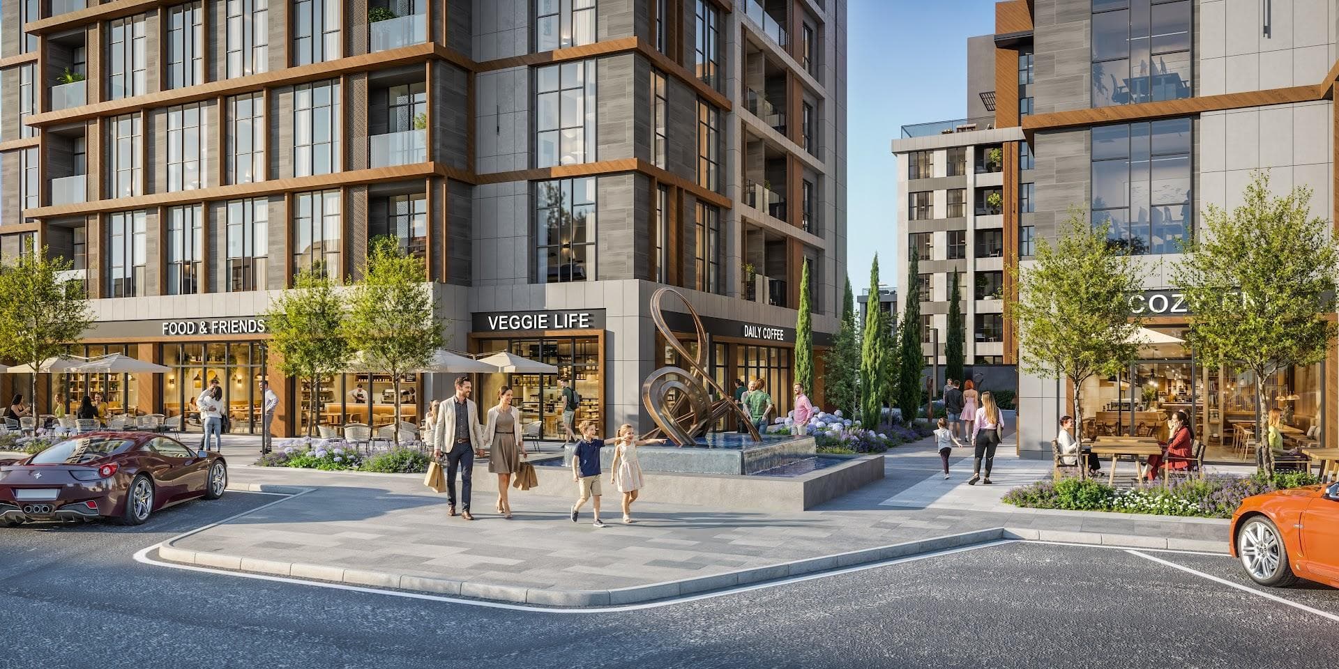 Pedestrian plaza with a sculpture fountain between shops and cafes at the entrance to the site
