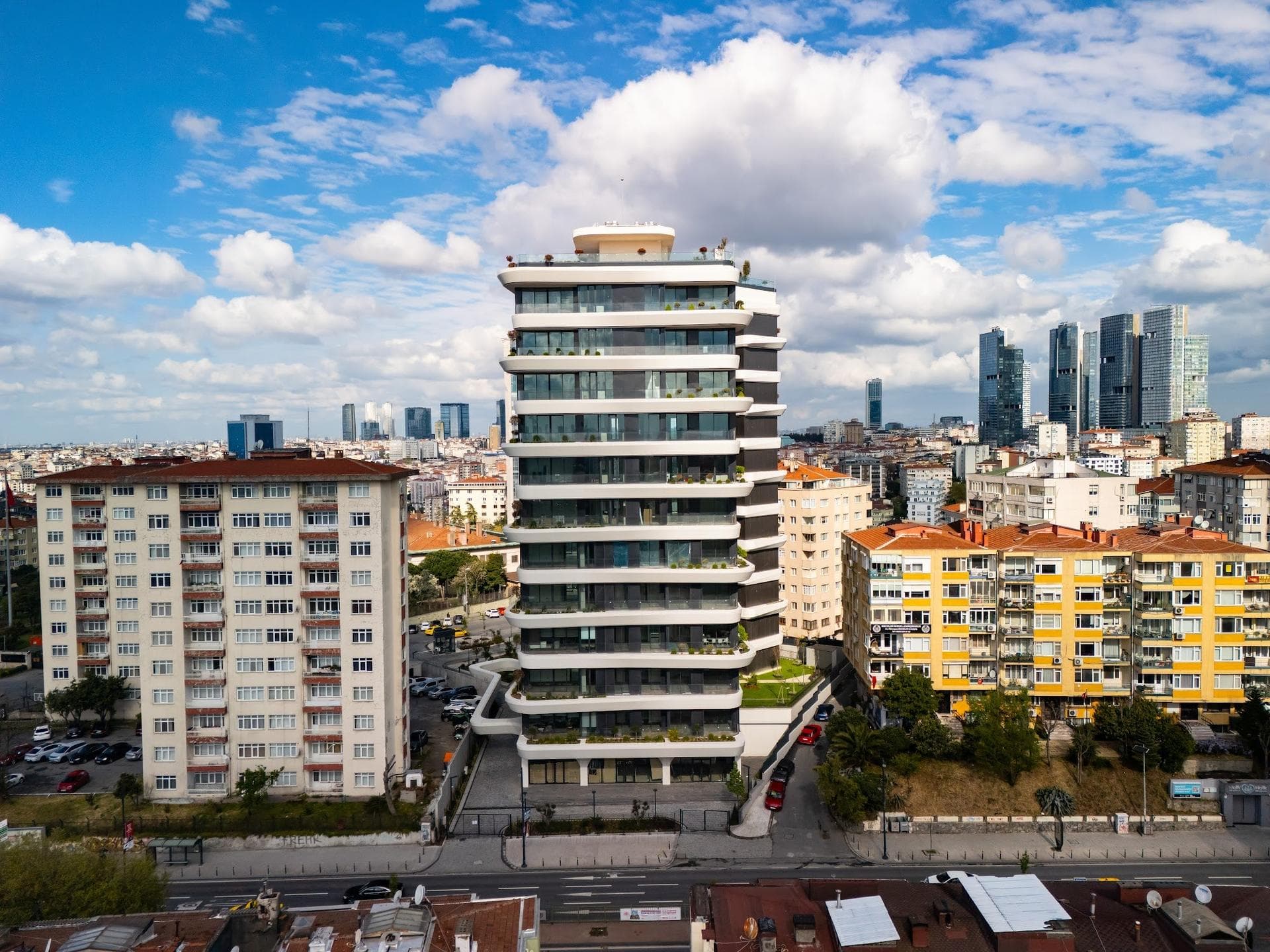 Drone photo of the finished tower seen from above Barbaros Boulevard, with curved white terrace bands, glazed apartments and the Levent towers on the skyline