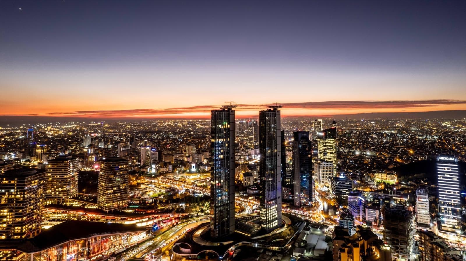Ciftci Towers lit up at dusk among the high-rises of Istanbul's business district