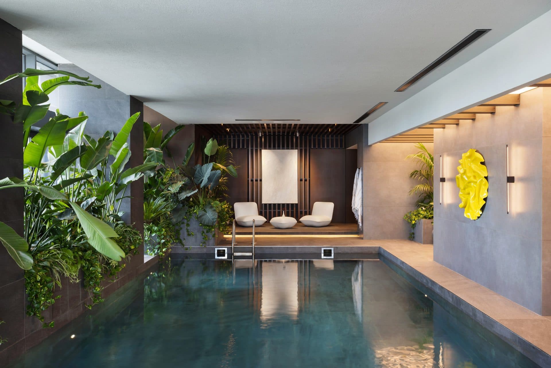 Indoor swimming pool with tropical planting and loungers