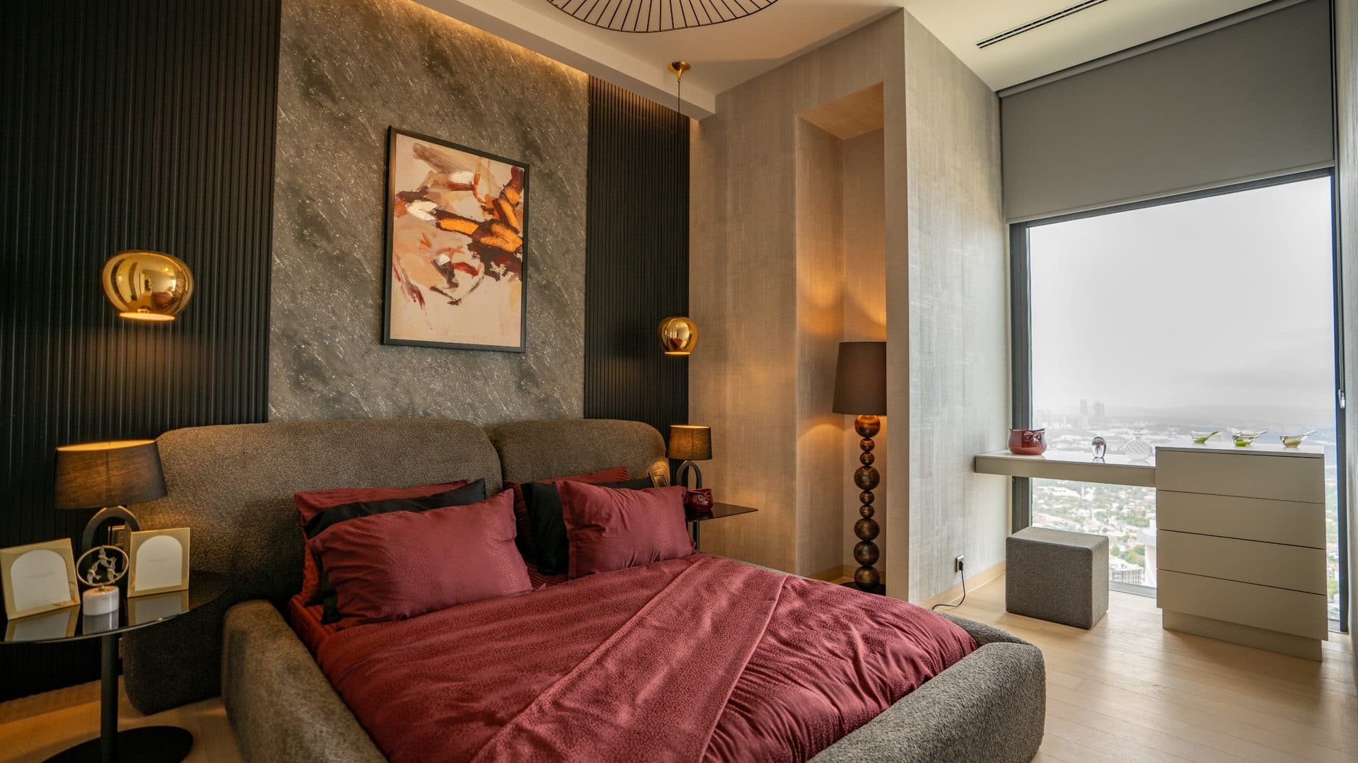 Bedroom with a double bed, a desk and a large window over the city