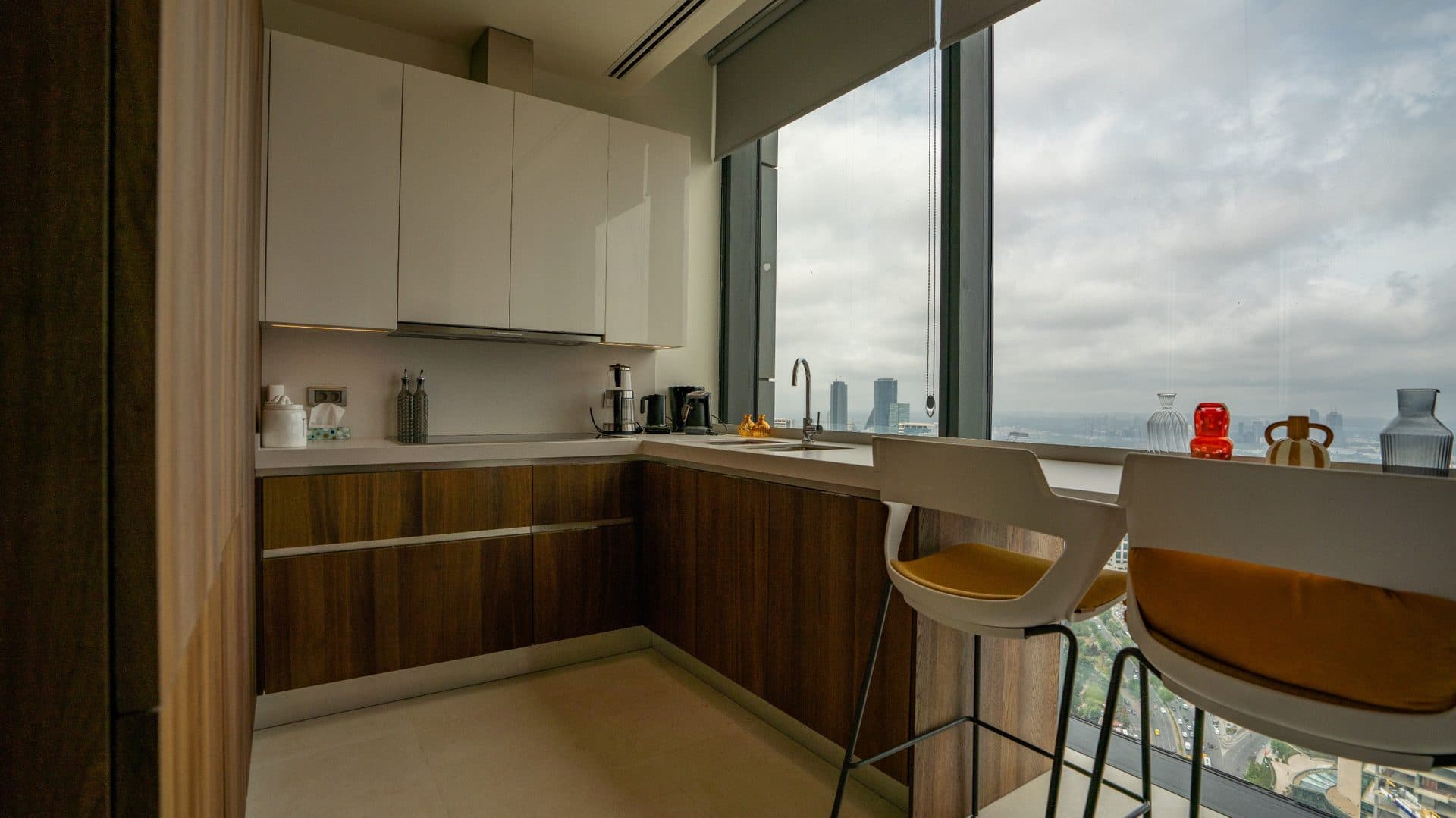Kitchen with white upper cabinets, wood-finish lower units and a breakfast bar at the window