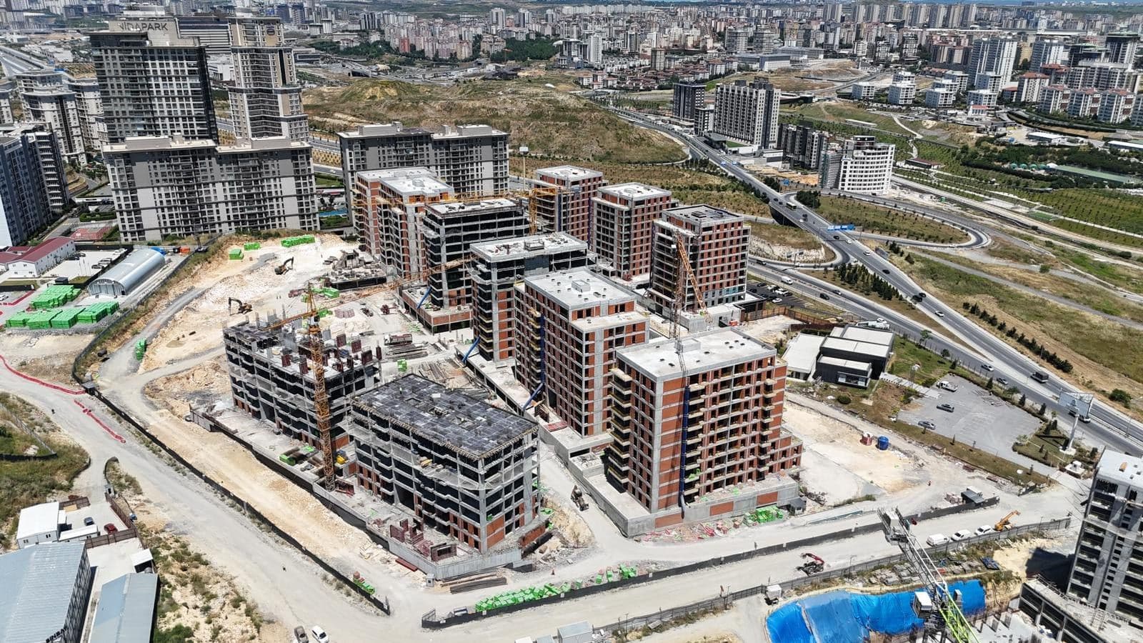 Drone photo from June 2026 from the south, with several blocks at full height and two blocks in the foreground still rising