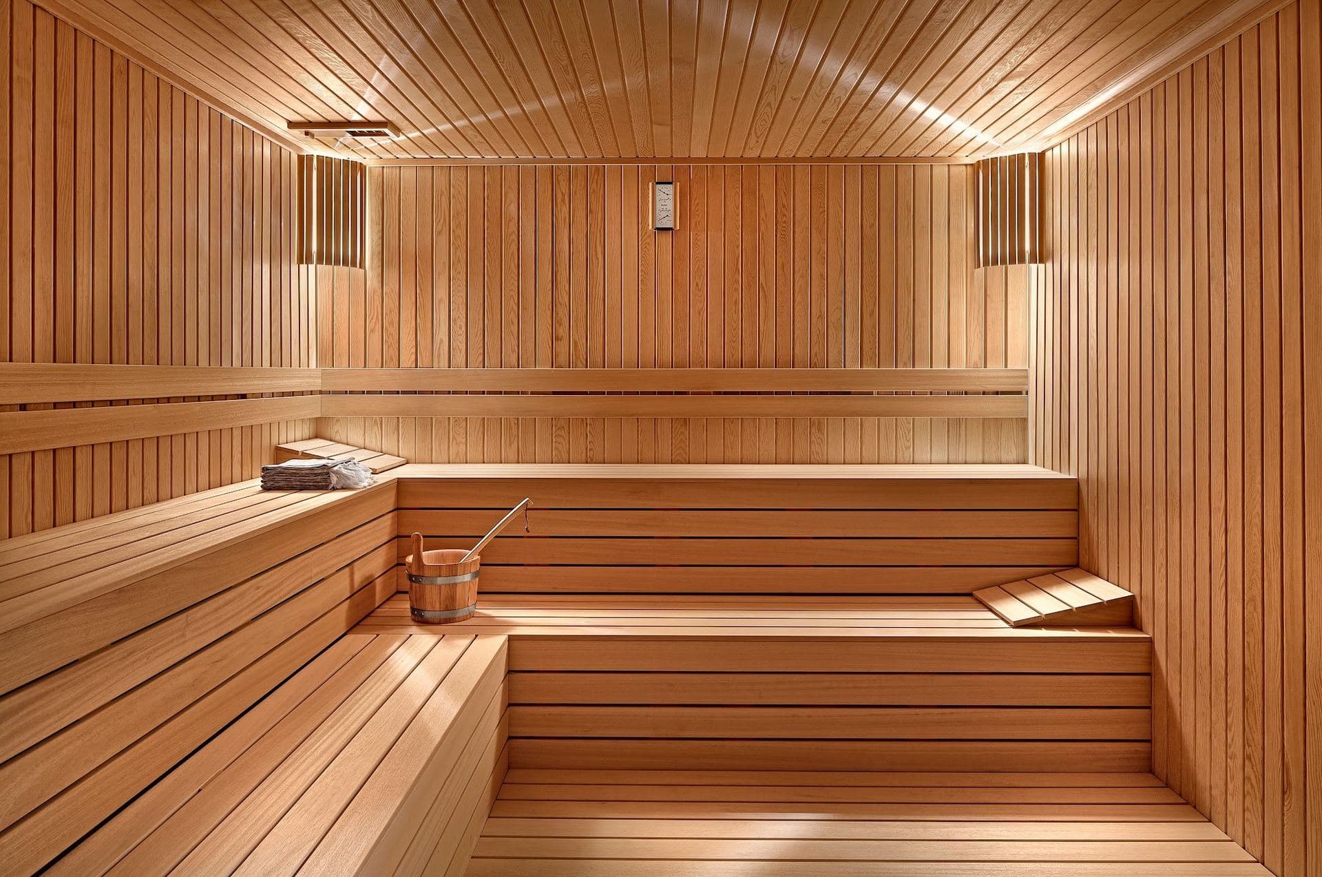 Wood-panelled sauna with tiered benches and warm wall lights