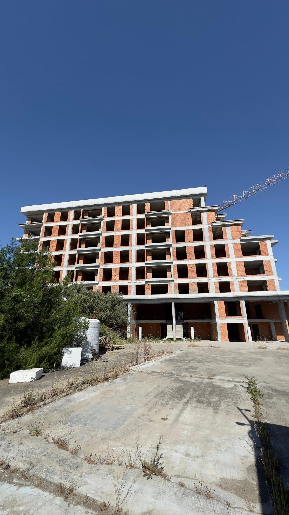 The C block under construction, its concrete frame and brick walls complete, with a tower crane beside it