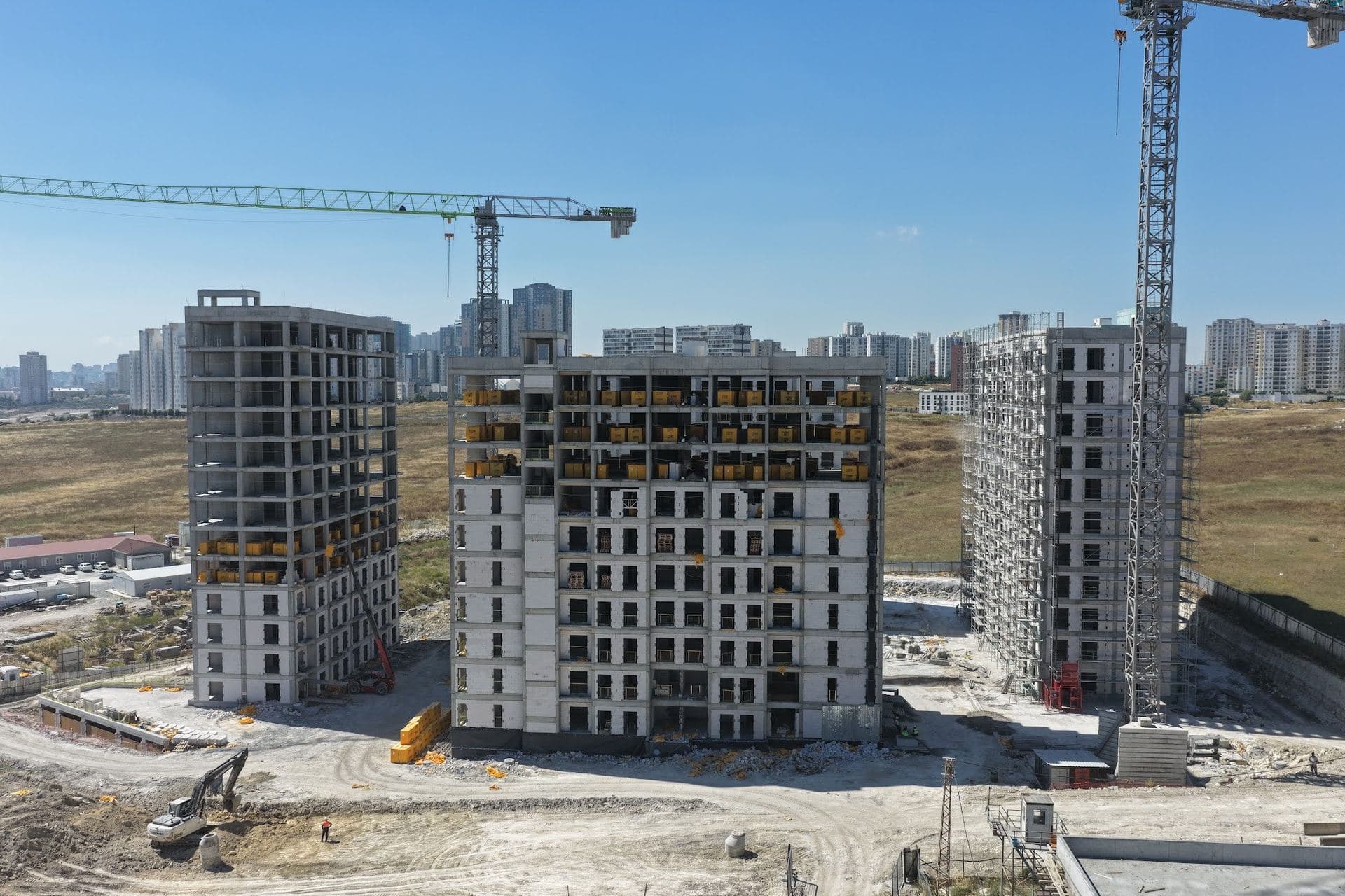 Drone photo of three blocks under construction with tower cranes, their concrete frames complete and walls partly built