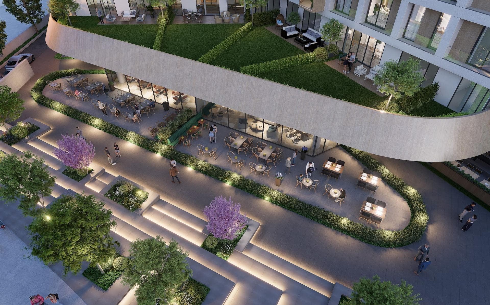 Evening aerial render of ground-floor restaurant terraces and stepped, lit gardens below the curved edge of the podium, with lawns on the podium roof above