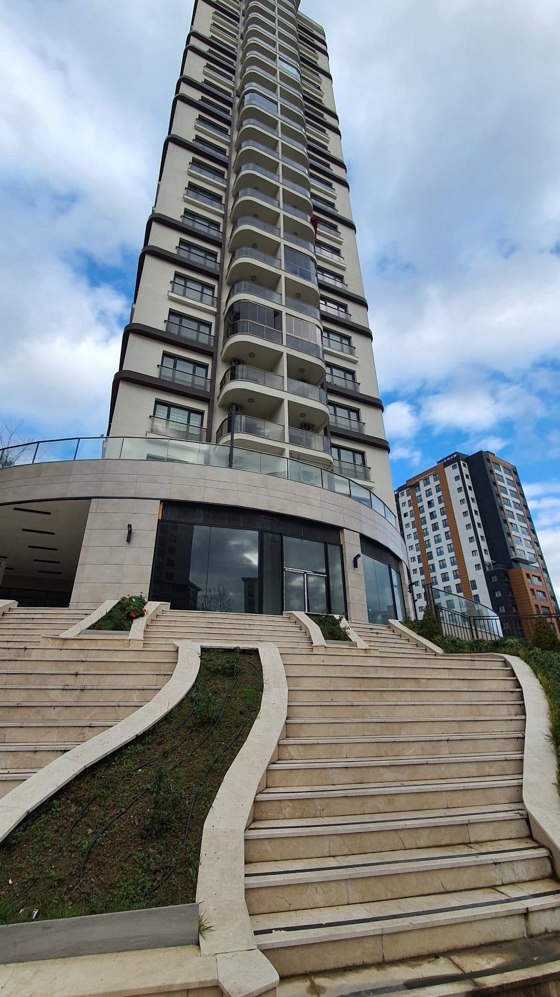 Residential tower rising above a curved glass shopfront and wide stone steps