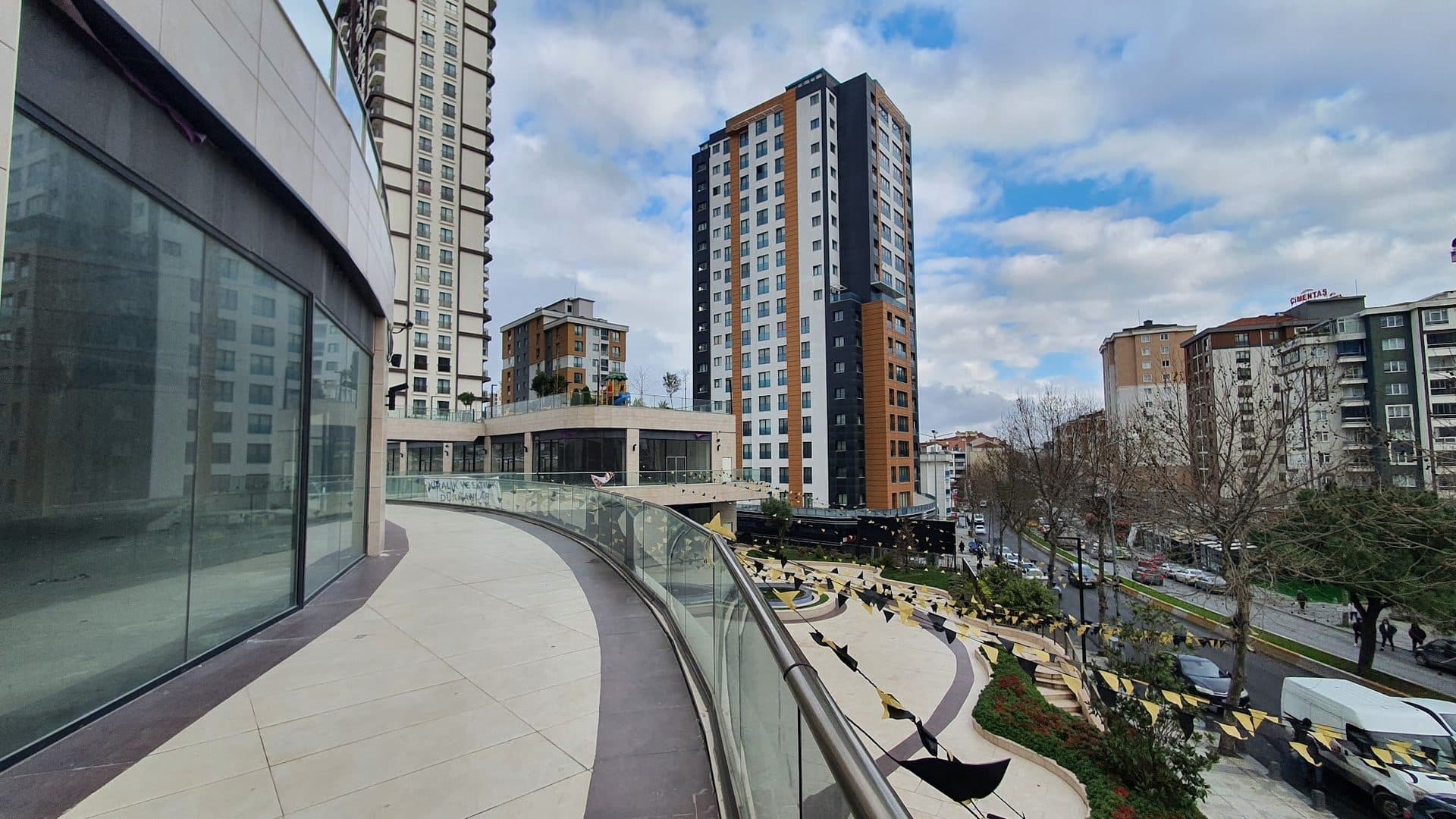 Curved upper terrace beside glazed shopfronts, with the street below