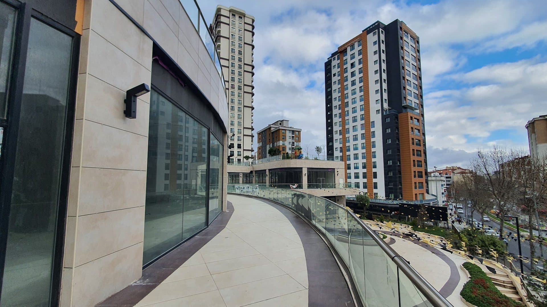 Glazed shopfront along a curved walkway, with towers behind