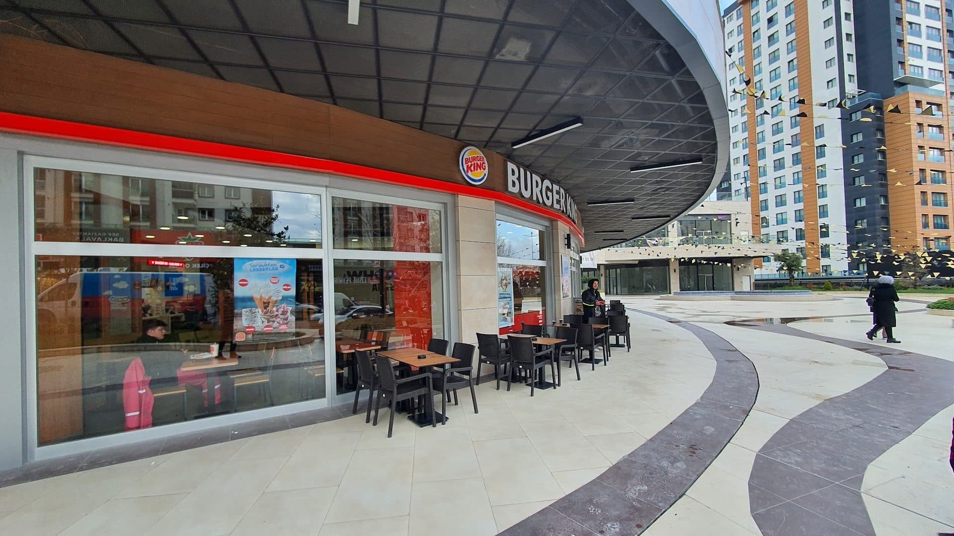 Corner fast-food restaurant with outdoor seating under a curved canopy