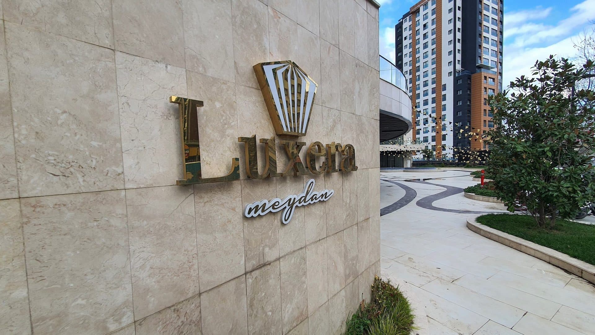 Luxera Meydan sign on a stone-clad wall beside the plaza