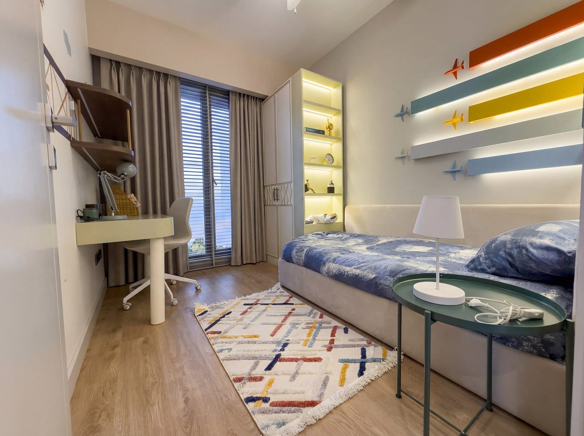 Photo of the furnished 2+1 show apartment: second bedroom set up as a child's room with a daybed, a desk and colorful wall shelves