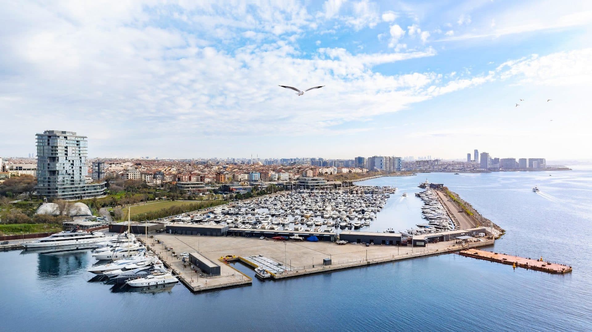 Aerial view of the marina's superyacht quay and yacht basin, with the tower on the left and the coast behind