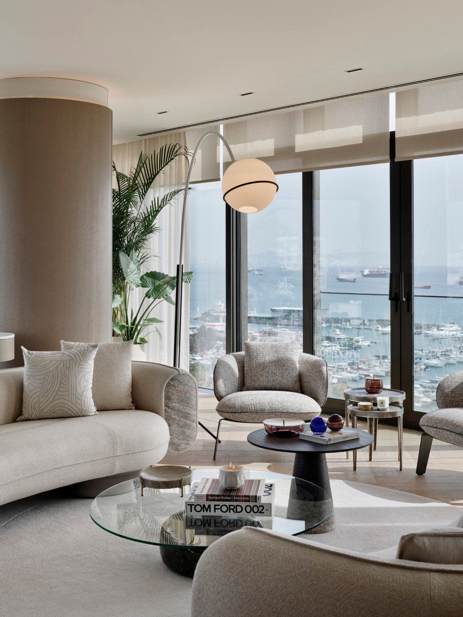Seating corner by the windows with armchairs and a glass coffee table, the marina and the sea beyond