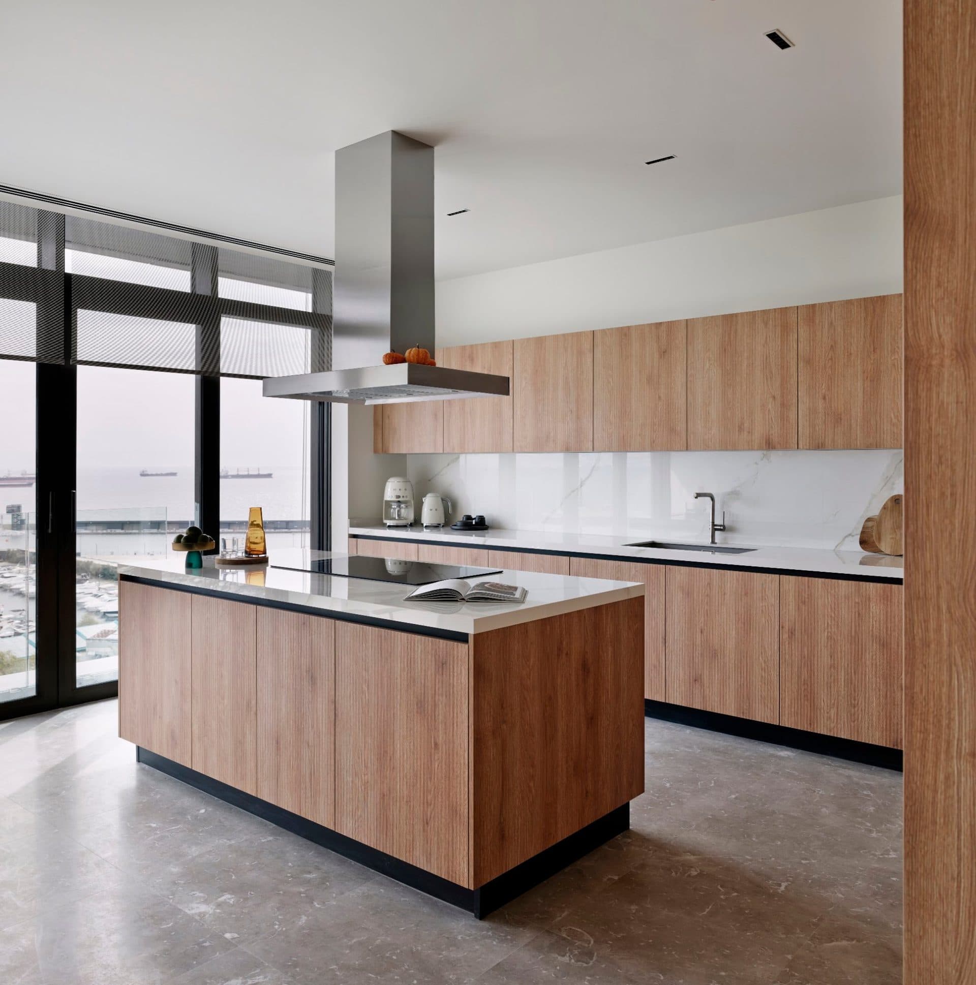 Kitchen with wood-finish cabinets, a central island, stone countertops and a steel hood, with sea views through the windows