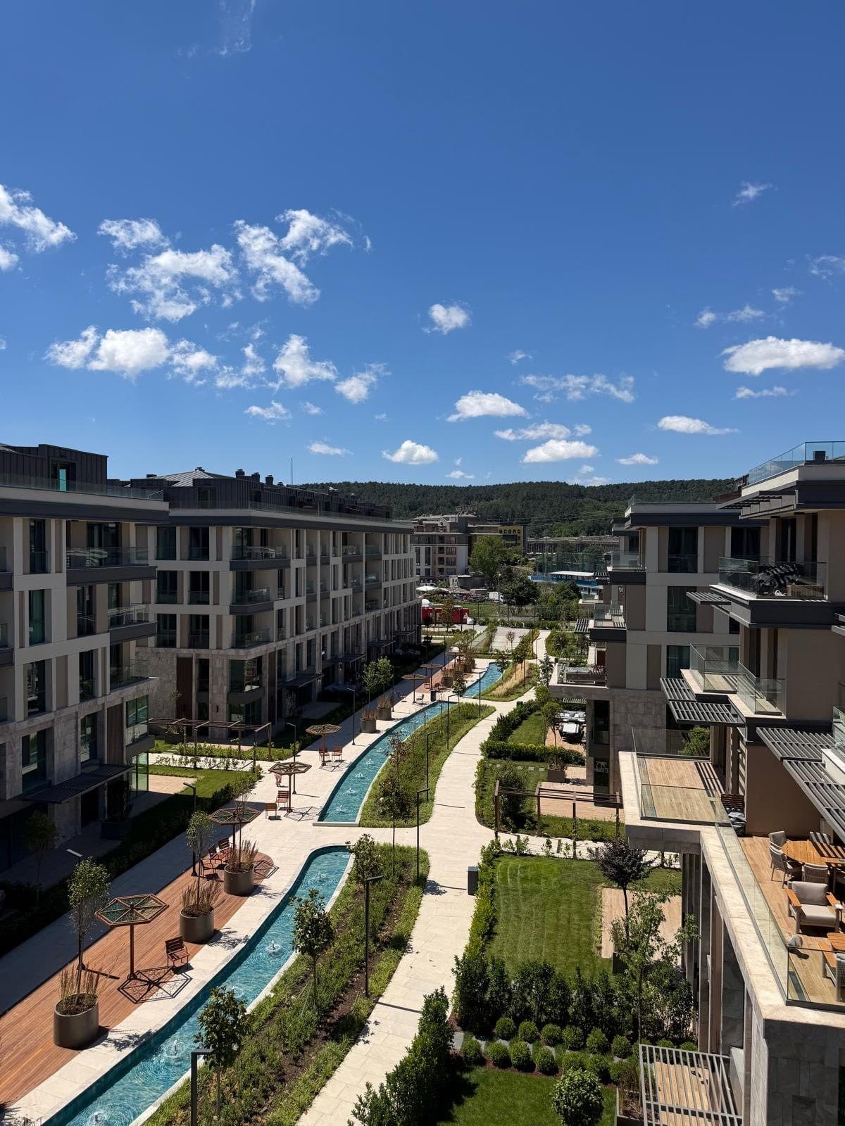 Photo looking down the central promenade between two rows of finished blocks, with water channels, timber decks, lawns and private gardens