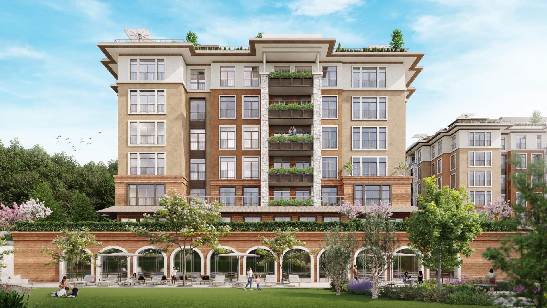 Front of a residential block with an arched brick base, lawn and planted balconies