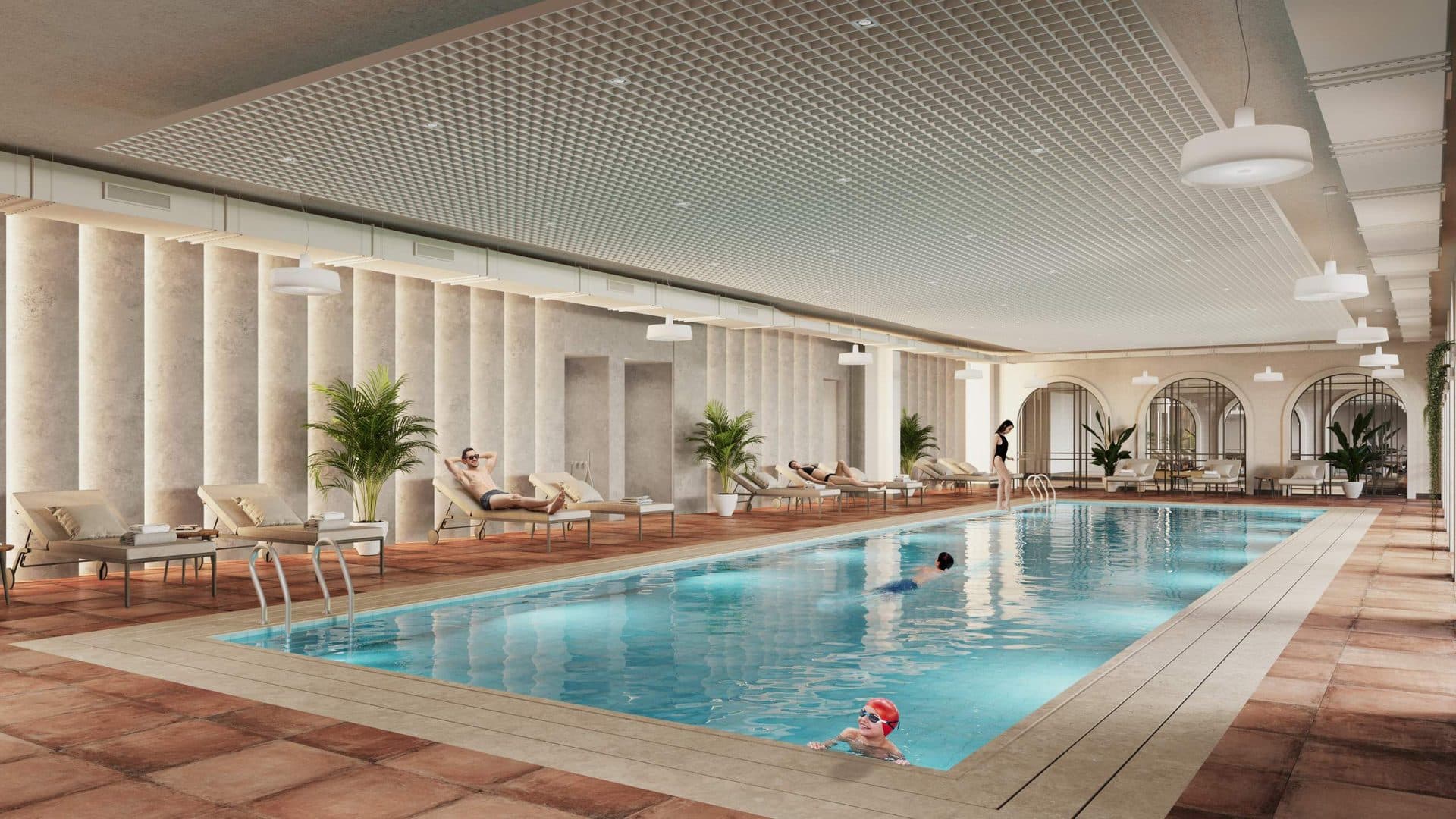 Indoor swimming pool with sun loungers and arched windows