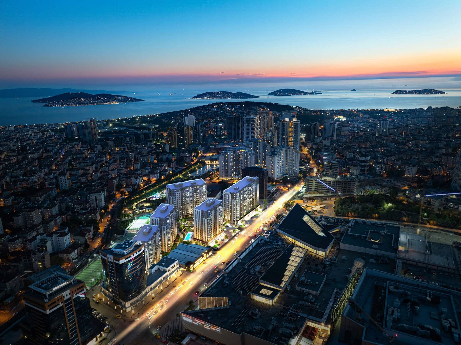Evening aerial view of the lit Ozak Dragos blocks, with the Princes' Islands on the horizon