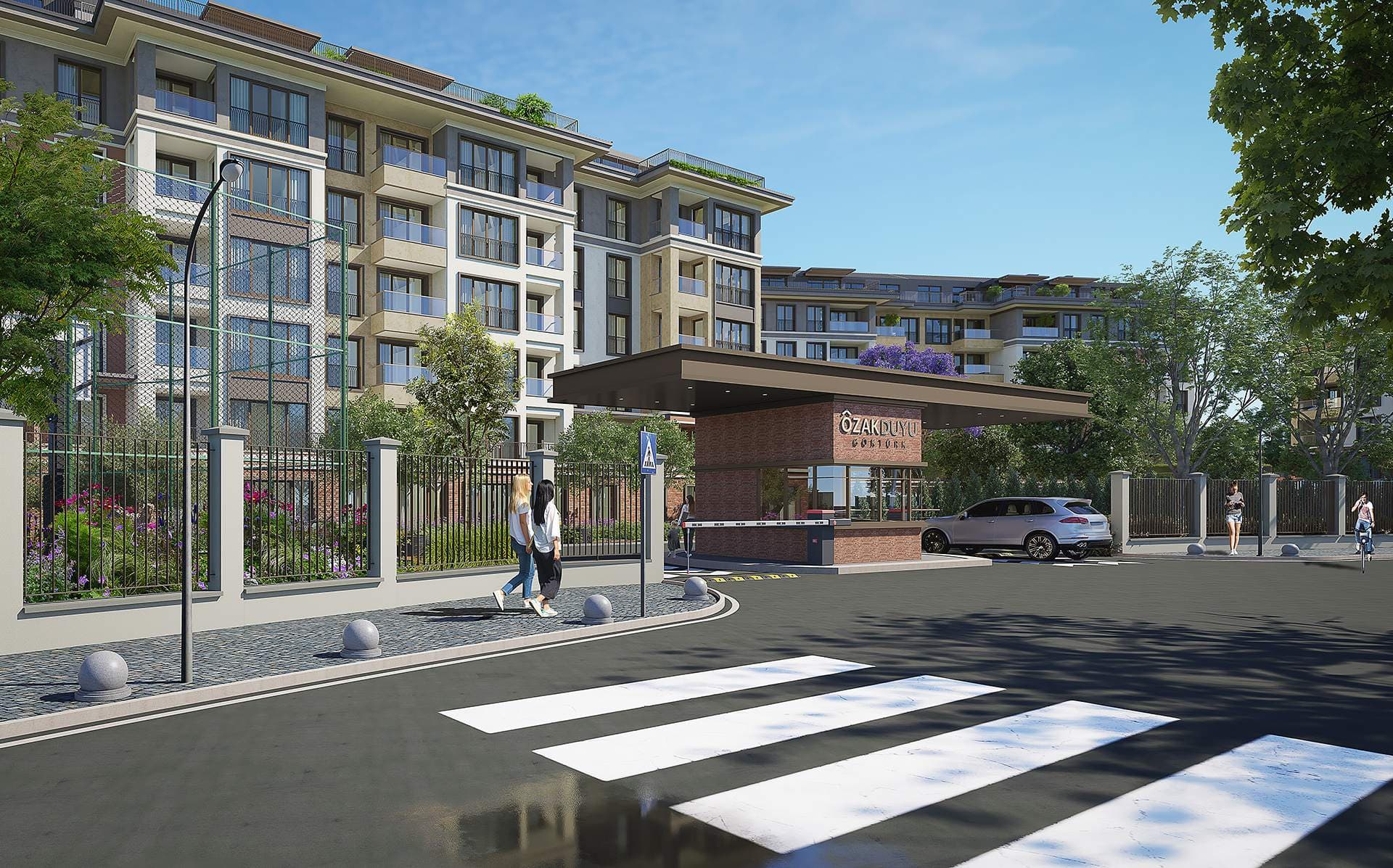 Site entrance with a gatehouse and barrier, residential blocks behind the fence