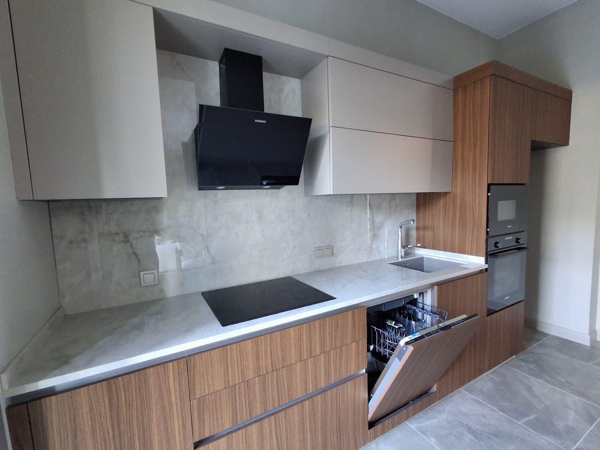 Show apartment kitchen with wood-finish and light gray cabinets, a built-in oven, an induction hob and a dishwasher