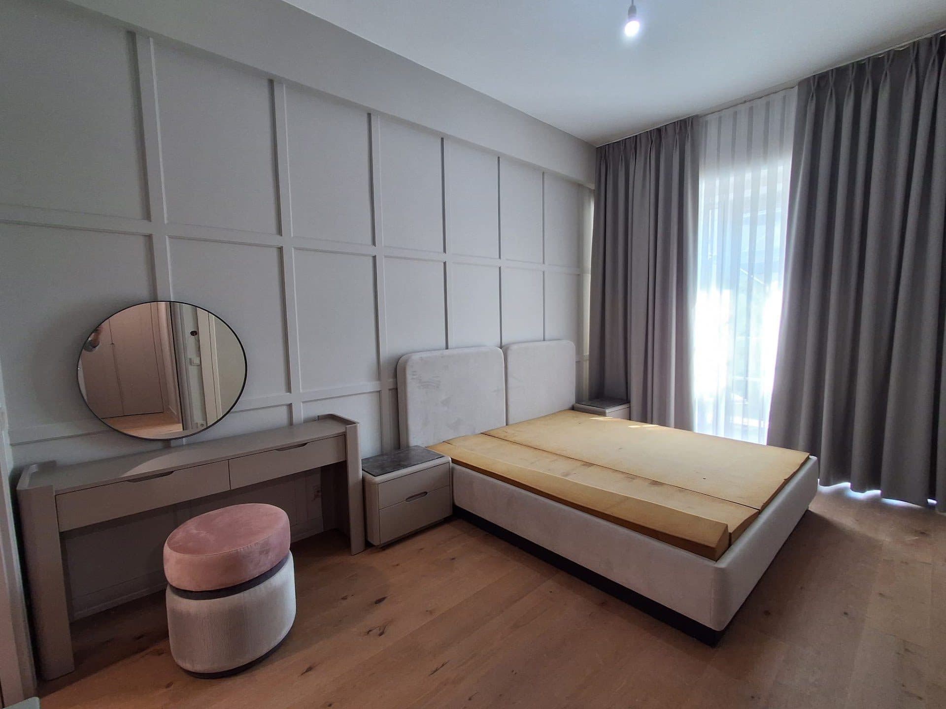 Bedroom with paneled walls, a double bed, a dressing table and floor-length curtains