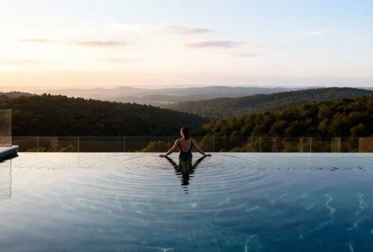 Rendering of a woman in an infinity pool looking out over wooded hills at sunset