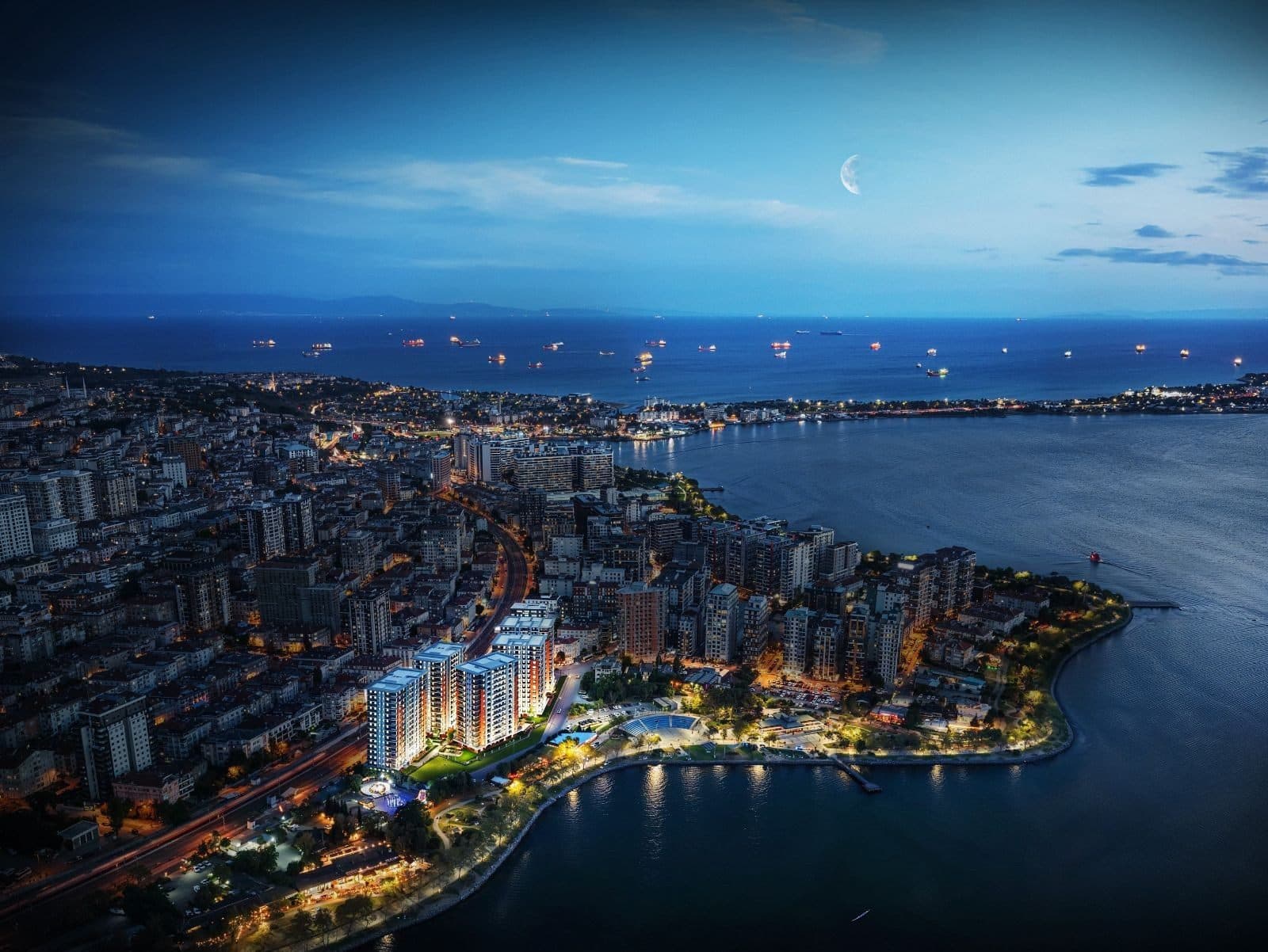 Evening aerial view of the lit Yali 360 towers beside Kucukcekmece Lake, with the Sea of Marmara behind