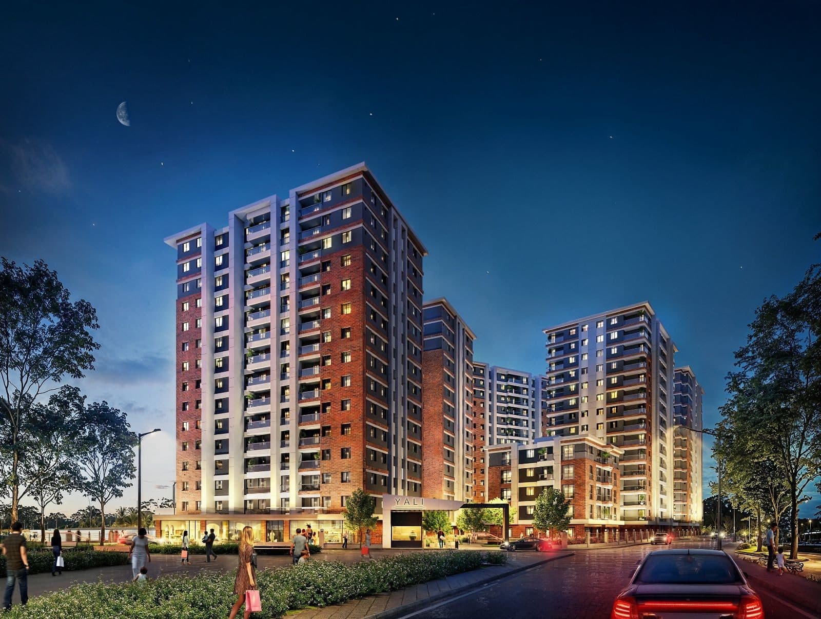 Yali 360 towers at night seen from the street, with shopfronts and the site entrance at ground level